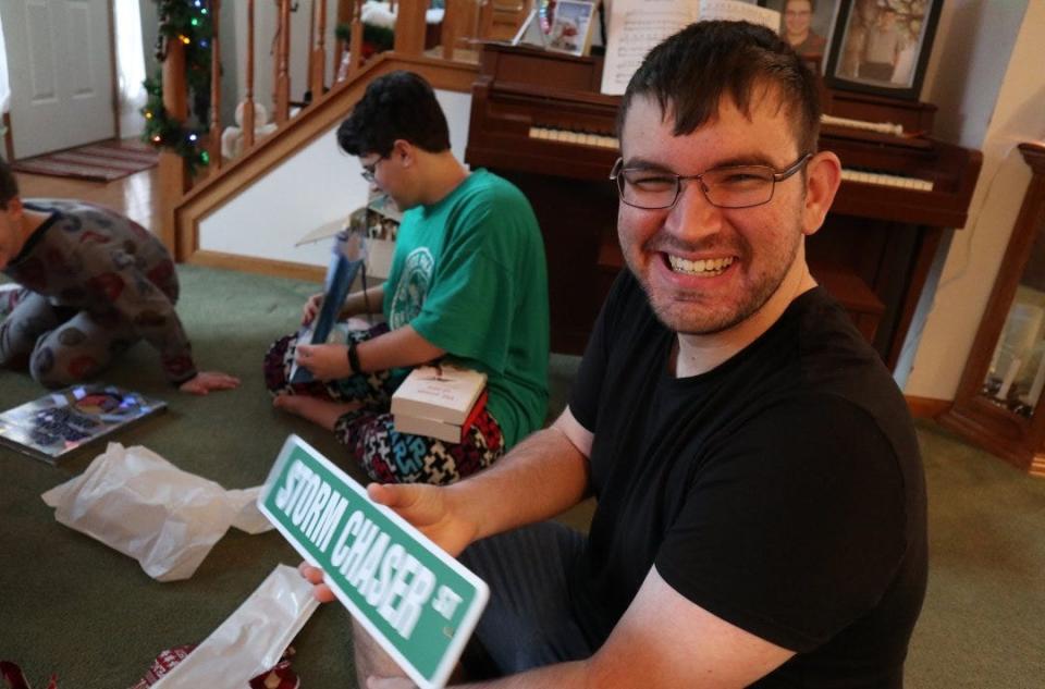 Gavin Short, 19, is pictured holding a storm chaser sign he received last Christmas.