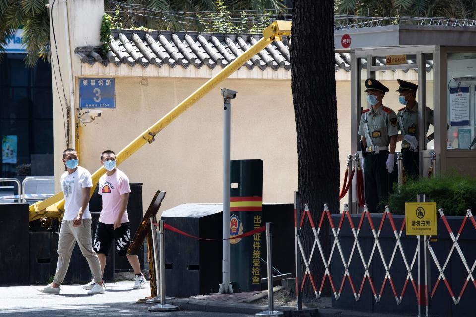 Plain clothes security personnel pass near Chinese paramilitary policemen guarding outside the United States Consulate in Chengdu in southwest China's Sichuan province on Sunday, July 26, 2020. China ordered the United States on Friday to close its consulate in the western city of Chengdu, ratcheting up a diplomatic conflict at a time when relations have sunk to their lowest level in decades. (AP Photo/Ng Han Guan)