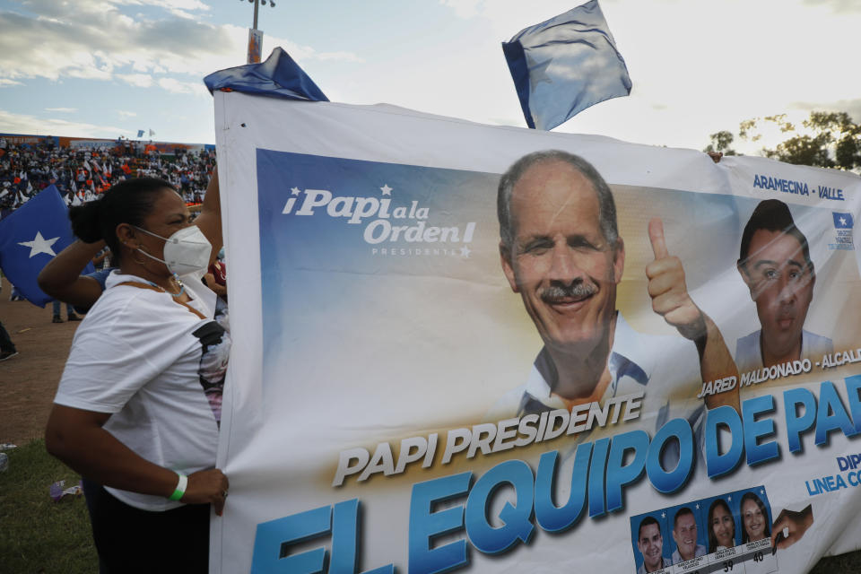 A supporter of National Party displays a banner showing presidential candidate Nasry Asfura during a closing campaign rally, in Tegucigalpa, Honduras, Sunday, Nov. 21, 2021. Honduras will hold its presidential election on Nov. 28. (AP Photo/Elmer Martinez)