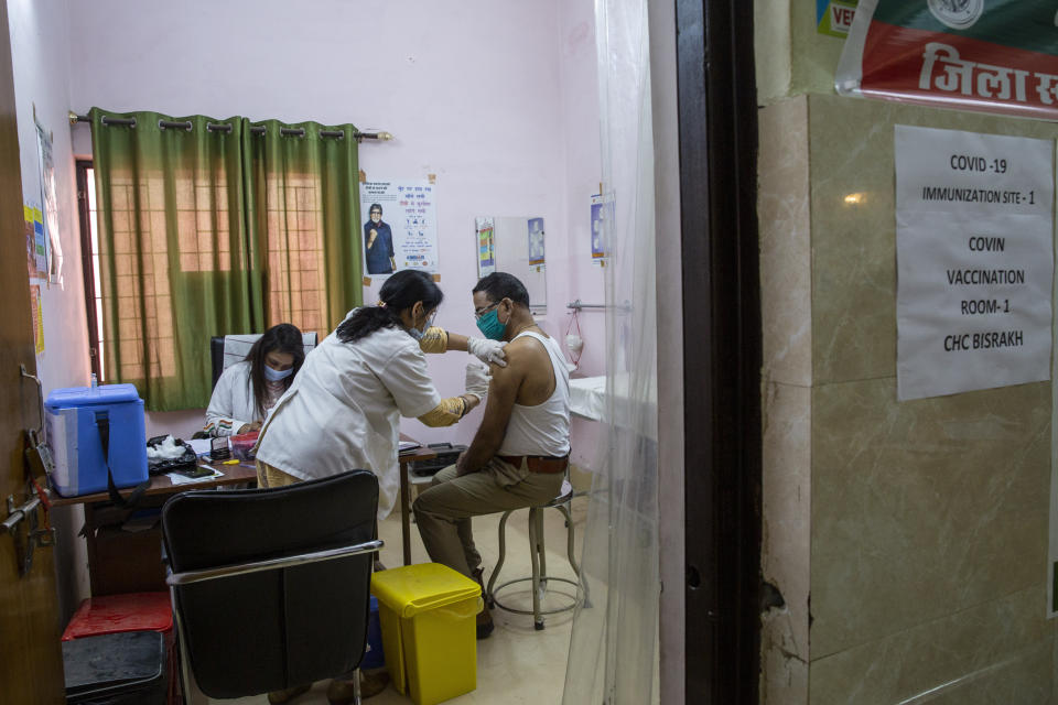 A health worker administers COVID-19 vaccine to a police officer at a health centre in Greater Noida, a suburb of New Delhi, India, Thursday, Feb. 11, 2021. When the coronavirus pandemic took hold in India, there were fears it would sink the fragile health system of the world’s second-most populous country. Infections climbed dramatically for months and at one point India looked like it might overtake the United States as the country with the highest case toll. But infections began to plummet in September, and experts aren’t sure why. (AP Photo/Altaf Qadri)