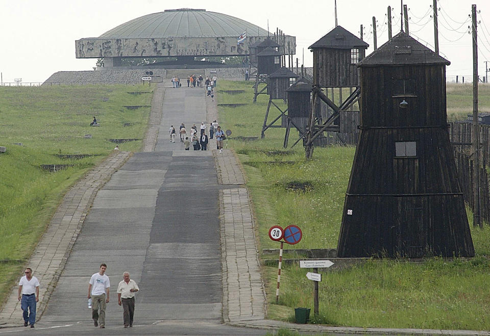 FILE - In this July 23, 2004 file photo, people are seen visiting the Majdanek camp in front of the Majdanek memorial, in Majdanek, southeastern Poland. A police spokesman in eastern Poland says an Israeli teen has admitted to dropping his pants at the former Nazi German death camp of Majdanek and is facing a fine. Andrzej Fijolek said Monday, Aug. 13, 2018 the 17-year-old, whose identity has not been released, was caught on CCTV cameras as he let down his pants by one of the wooden barracks at the Majdanek museum while on a school trip there Friday. (AP Photo/Czarek Sokolowski, file)