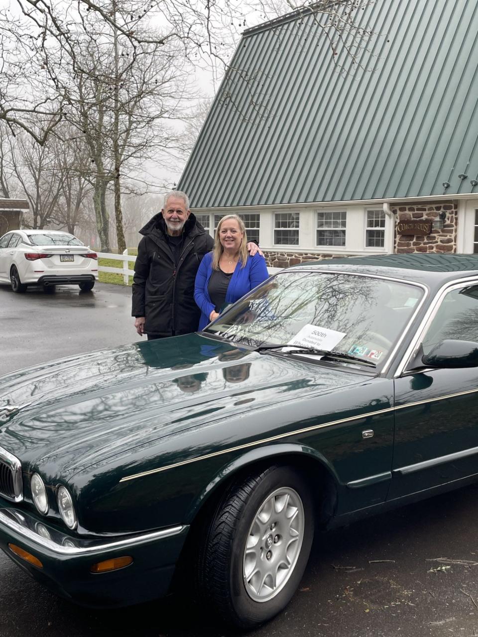 Philanthropist Gene Epstein and Erin Lukoss, CEO of the Bucks County Opportunity Council, stand beside a 1999 Jaguar that Epstein and his wife, Marlene, are donating to a woman being helped by the opportunity council as part of the Wheelz2Work program that Epstein founded to provide donated vehicles to people struggling economically who need a vehicle for employment and to meet educational goals.