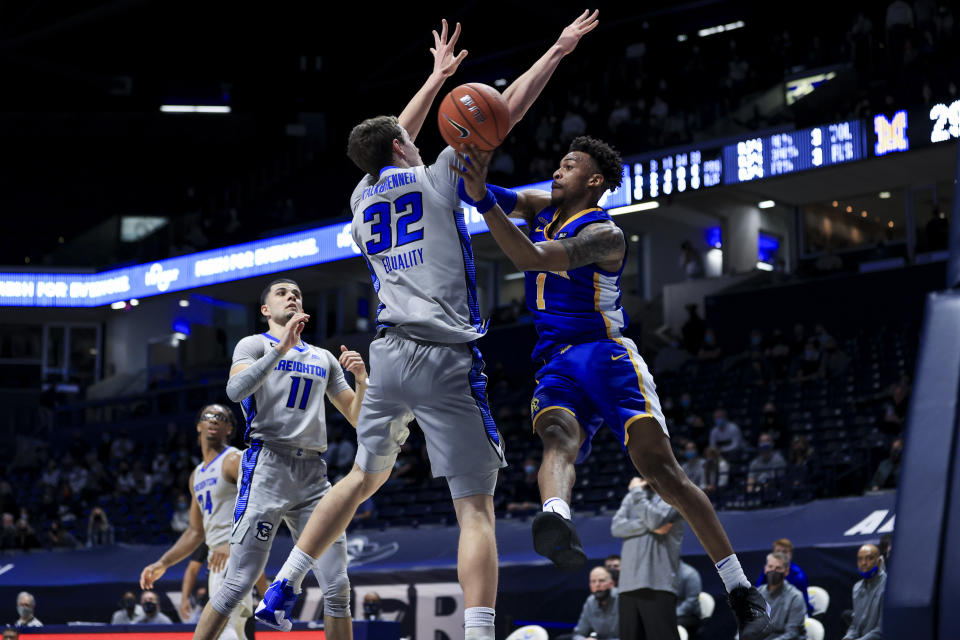 Creighton center Ryan Kalkbrenner, left, defends as Xavier guard Paul Scruggs passes the ball in the first half of an NCAA college basketball game, Saturday, Feb. 27, 2021, in Cincinnati. (AP Photo/Aaron Doster)