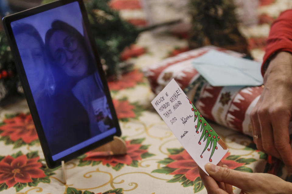 Celestina Comotti, 81, reads a Christmas card talking via video call with Alessia Mondello a donor unrelated to her who bought and sent her a Christmas present through an organization dubbed "Santa's Grandchildren", at the Martino Zanchi nursing home in Alzano Lombardo, one of the area that most suffered the first wave of COVID-19, in northern Italy, Saturday, Dec. 19, 2020. (AP Photo/Luca Bruno)
