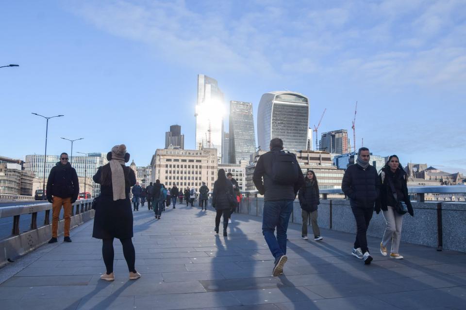 London, UK. 6th December 2022. People walk across London Bridge past the City of London skyline on a clear day as temperatures drop in the capital. Credit: Vuk Valcic/Alamy Live News