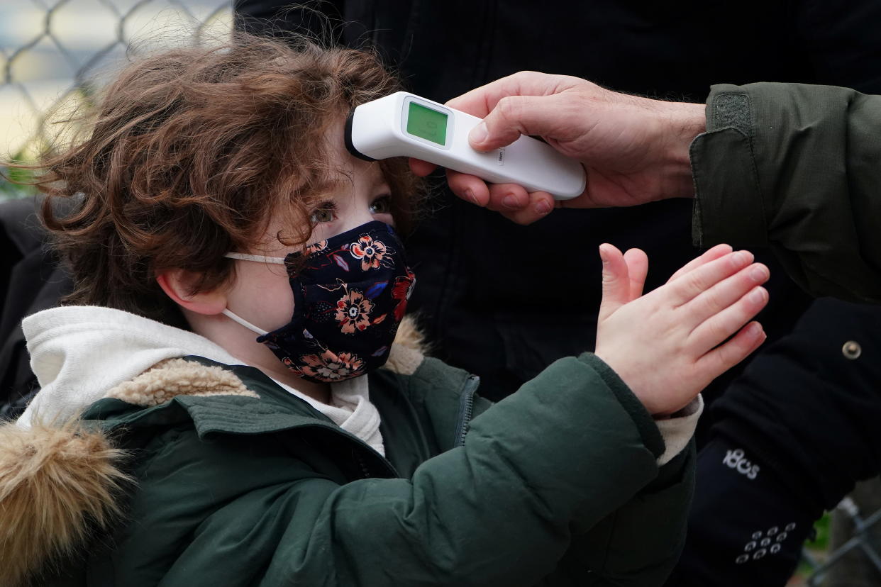 A child has his temperature checked as he rubs his hands with hand sanitizer before attending class at PS 361 on the first day of a return to class during the coronavirus disease (COVID-19) pandemic in the Manhattan borough of New York City, New York, U.S., December 7, 2020. REUTERS/Carlo Allegri