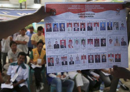 People watch as electoral officials show ballot papers during vote counting at a polling station in Jakarta April 9, 2014. REUTERS/Beawiharta