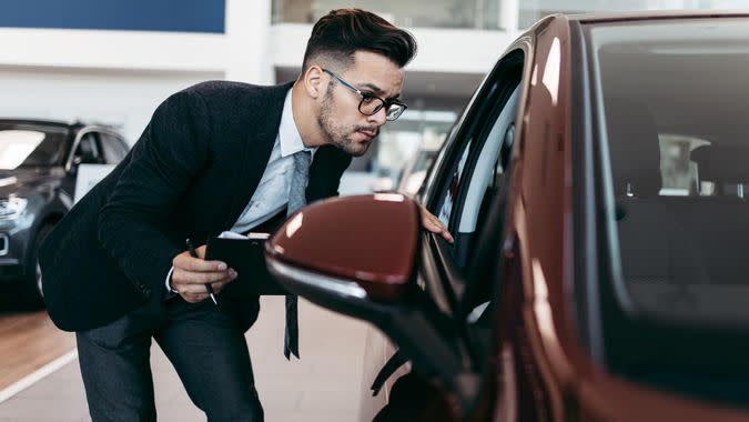 Car seller working in showroom and quality control checking of car details for the last time before buyer comes.