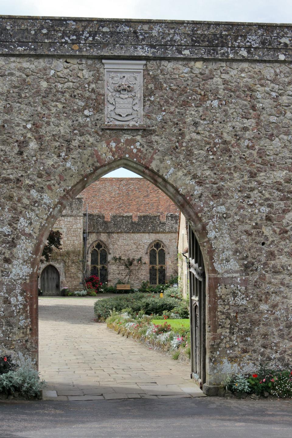 An walled entrance into Lympne Castle, with an open black iron gate.