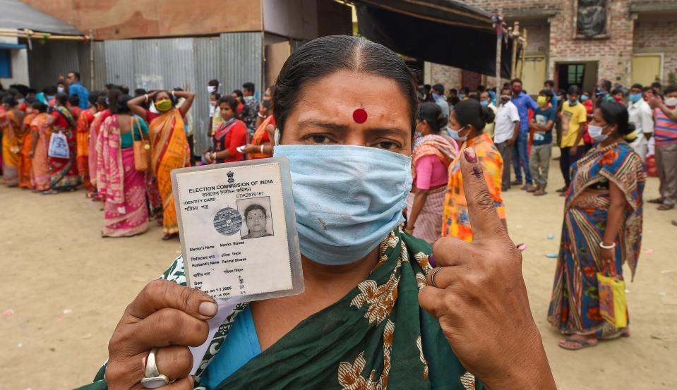 People show their voter cards as they wait in a queue to cast votes at a polling station, during the 6th phase of Assembly elections at Krishnanagar, in Nadia