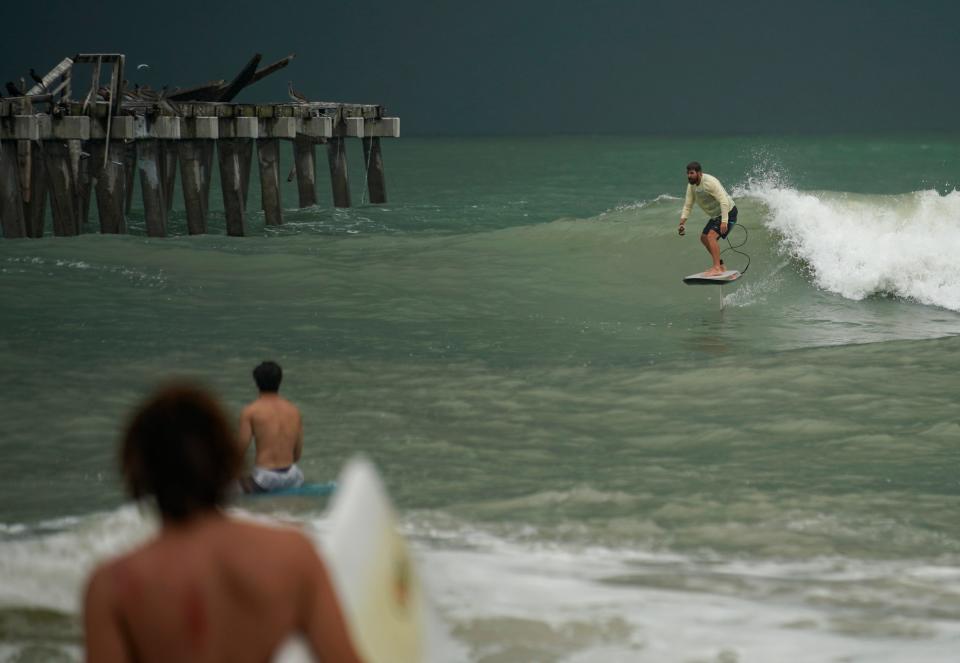 A person riding a foil board catches a wave as the outer bands of Hurricane Idalia pass at Naples Pier in Naples on Tuesday, Aug. 29, 2023.