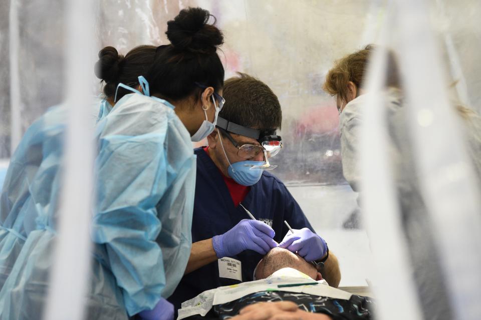 At center Michael Seitz performs dental work at Remote Area Medical’s pop-up clinic in Oak Ridge, Saturday Feb. 18, 2023.