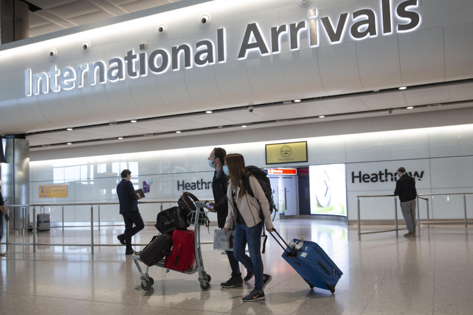 FILE - In this Monday, June 8, 2020 file photo, passengers wearing face masks arrive at London's Heathrow Airport. The British government said Friday, July 3, 2020, it is scrapping a 14-day quarantine rule for arrivals from about 60 countries deemed “lower risk” for the coronavirus, including France, Spain, Germany and Italy — but not the United States. (AP Photo/Matt Dunham, File)