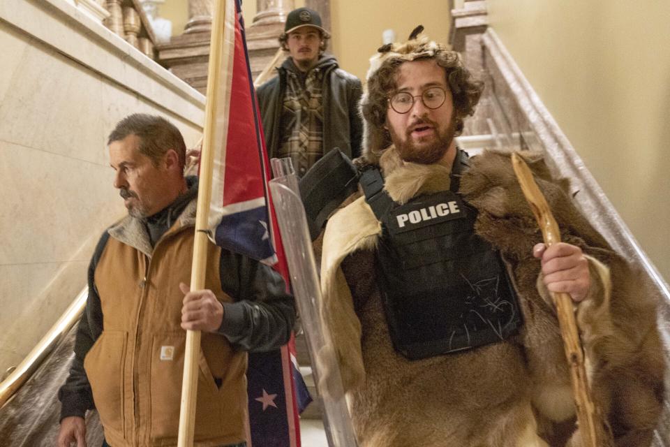 FILE - Insurrectionists loyal to President Donald Trump, including Aaron Mostofsky, right, and Kevin Seefried, left, walk down the stairs outside the Senate Chamber in the U.S. Capitol, in Washington, Jan. 6, 2021. A federal trial is scheduled to start on Monday, June 13, for Seefried and his son Hunter who have been charged with storming the U.S. Capitol together. (AP Photo/Manuel Balce Ceneta, File)