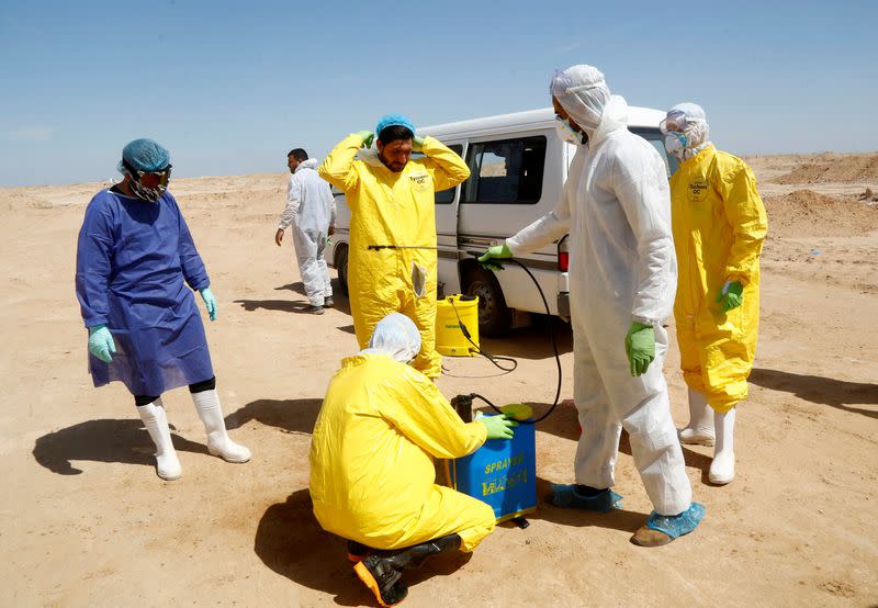 Iraqi Shiite volunteers from Hashid Shaabi and members of a medical team disinfect themselves after the burial of a man who passed away due to coronavirus disease (COVID-19), at a new cemetery for victims of coronavirus, on the outskirt of Najaf