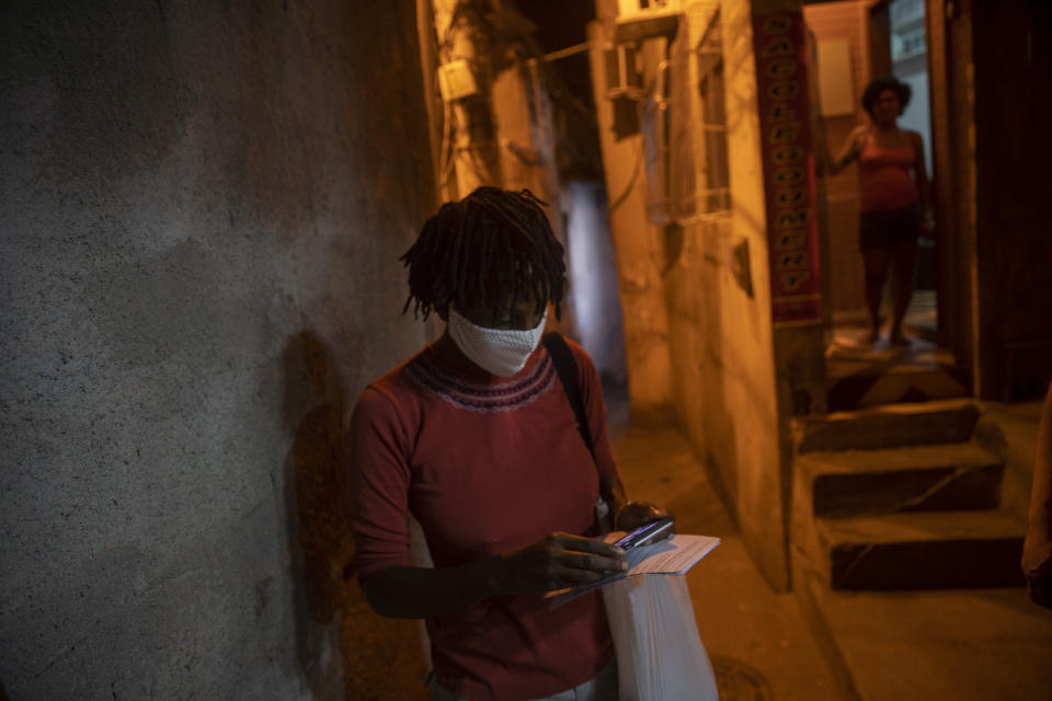 A resident watches the "Tempero de Criola" perform in the Turano favela amid the new coronavirus pandemic, in Rio de Janeiro, Brazil, Friday, June 19, 2020. A group of musicians playing Samba offered a small concert to the residents of Turano favela, most of whom remain quarantined to curb the spread of COVID-19. Residents could watch the performance from their windows, balconies or via internet. (AP Photo/Silvia Izquierdo)