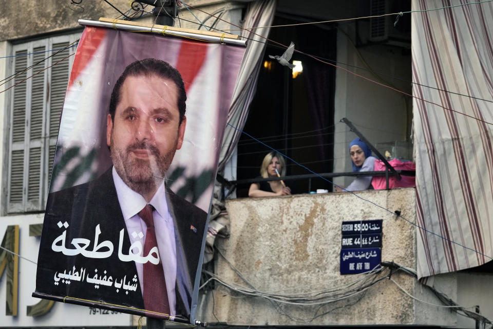 Women sit on their apartment balcony and smoke a water pipe next to of a poster of former Lebanese Prime Minister Saad Hariri with Arabic reading "Boycott (the elections)," in Beirut, Lebanon, Tuesday, May 10, 2022. Given Lebanon's devastating economic meltdown, Sunday's parliament election (May 15) is seen as an opportunity to punish the current crop of politicians that have driven the country to the ground. (AP Photo/Bilal Hussein)