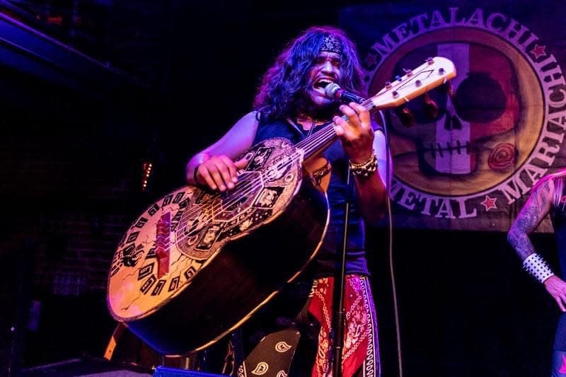 A member of the band Metalachi: The World's First and Only Heavy Metal Mariachi Band, performs on stage.