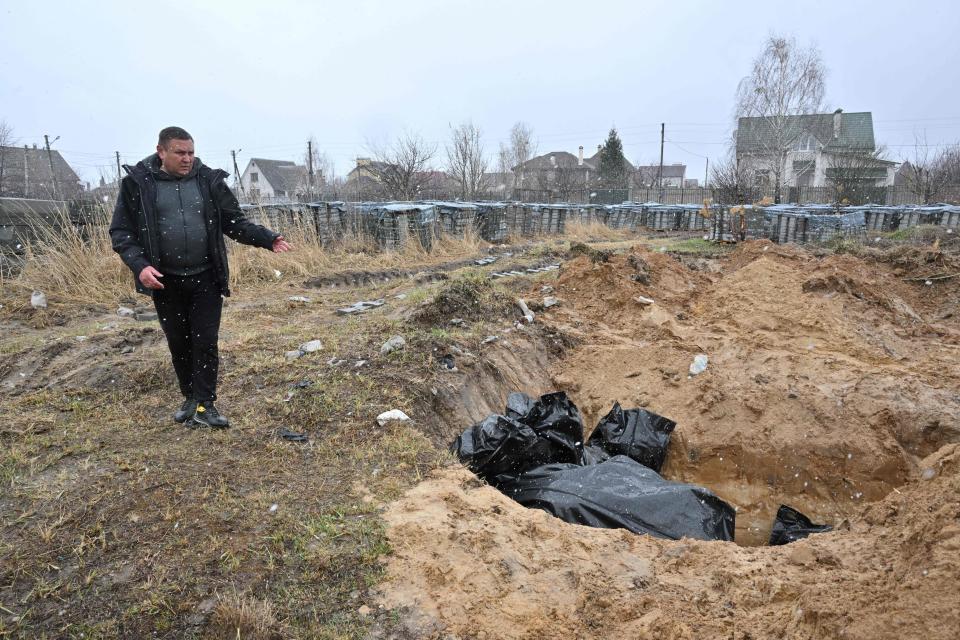 A man gestures at a mass grave in the town of Bucha, northwest of the Ukrainian capital Kyiv, April 3, 2022. / Credit: SERGEI SUPINSKY/AFP/Getty