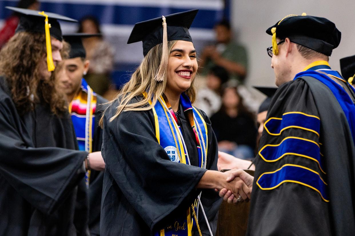 Haley Ruiz shakes hands with Dean of Natural Sciences Jonathan Hodge during commencement at St. Edward’s University on Dec. 15. Ruiz started college when she was 14.