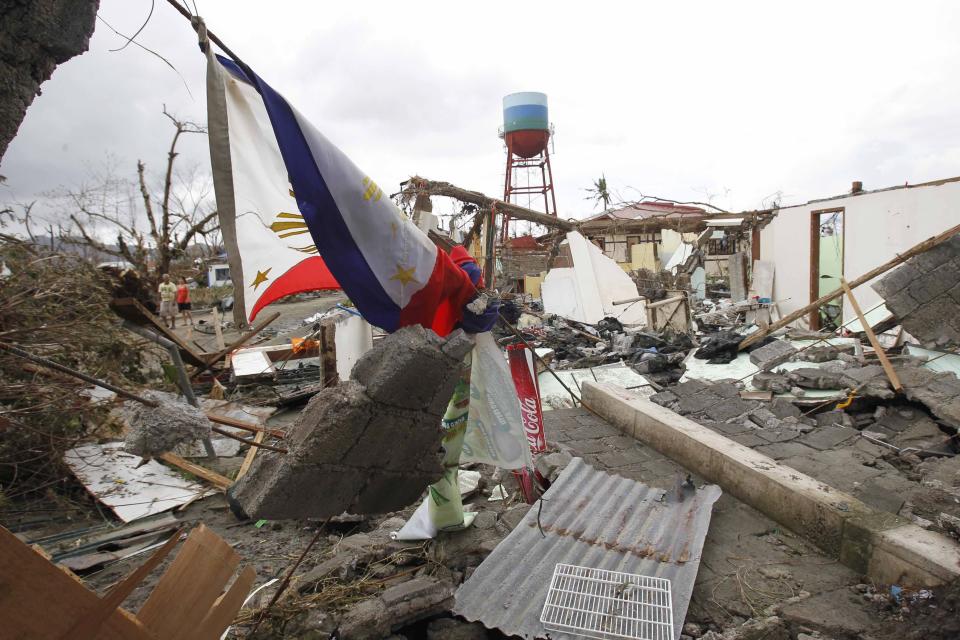 A Philippine flag is seen among damaged houses after super Typhoon Haiyan battered Tacloban city