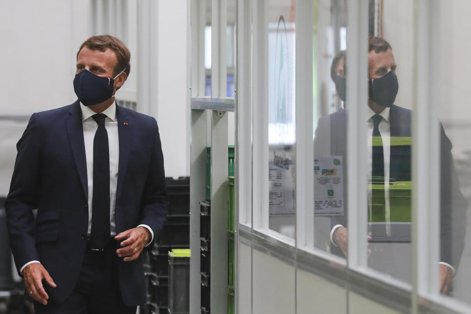 French President Emmanuel Macron, center, wearing a protective face mask, as he visits a Valeo manufacturer plant, in Etaples, , northern France, Tuesday May 26, 2020. France's government is injecting more than 8 billion euros ($8.8 billion) to save the country's car industry from huge losses wrought by virus lockdowns, and wants to use the crisis to make France the No. 1 producer of electric vehicles in Europe. (Ludovic Marin, Pool via AP)