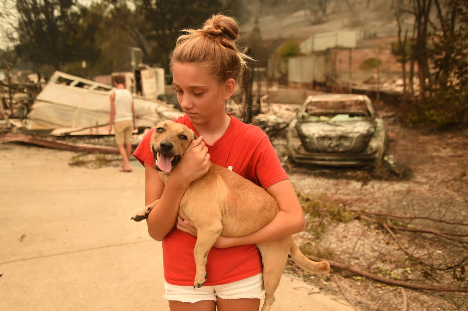 Kambryn Brilz, 12, holds her dog Zoe in front of what remains of her burnt home after she was returned safely by a neighbor during the Carr Fire.