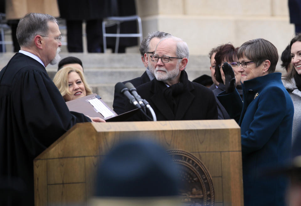 Gov. Laura Kelly, right, takes the oath of office from Chief Justice Lawton Nuss, left, on the Statehouse steps in Topeka, Kan., Monday, Jan. 14, 2019. Kelly's husband Ted Daugherty, center, holds a Bible for the ceremony. (AP Photo/Orlin Wagner)