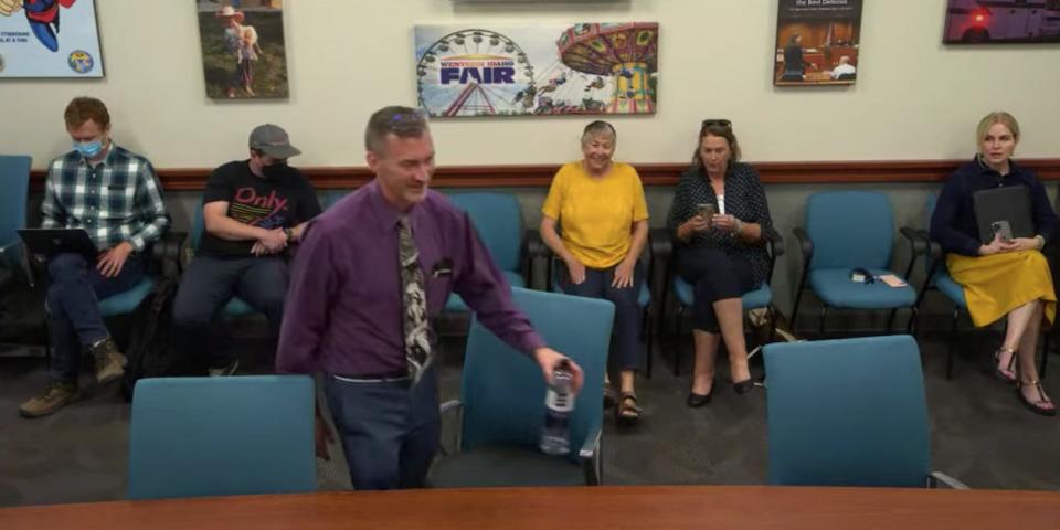 Dr Ryan Cole taking his seat to be interviewed for the CDH Board on August 9, 2021. Members of the public sit behind him.