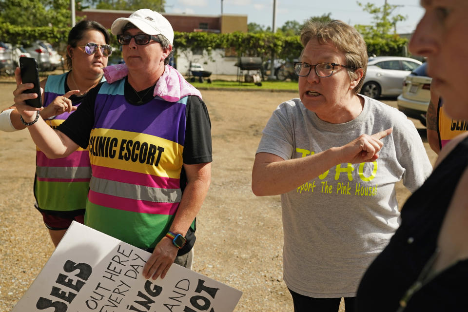 Surrounded by clinic escorts, Dr. Cheryl Hamlin, right, yells at anti-abortion activist John Busby, unseen, outside the Jackson Women's Health Organization clinic in Jackson, Miss.,Thursday, July 7, 2022. Hamlin is one of a rotating group of physicians that provided abortions at the clinic. The clinic was the only facility that performed abortions in the state. However, on Tuesday, a chancery judge rejected a request by the clinic to temporarily block a state law banning most abortions. (AP Photo/Rogelio V. Solis)