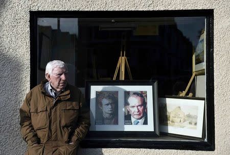 A man stands next to a shop displaying a portrait of Martin McGuinness during his funeral at St Columba's Church in Londonderry, Northern Ireland, March 23, 2017. REUTERS/Clodagh Kilcoyne