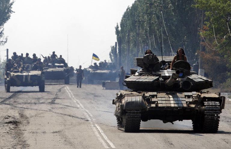 Ukrainian tanks pass by the small eastern city of Vuglegirsk, Donetsk region, on August 14, 2014