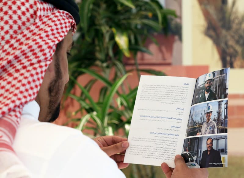 A Saudi man reads the prospectus of Aramco IPO, in Riyadh