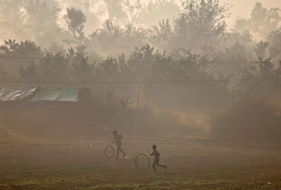 <p>Kinder in Neu-Delhi spielen mit alten Reifen – der Smog in der Nähe des Yamuna, dem wichtigsten Nebenfluss des Ganges, ist an diesem Morgen ganz besonders stark zu sehen. (Bild: Reuters) </p>