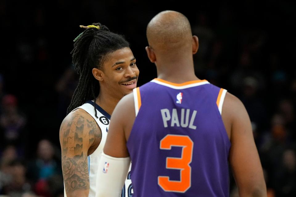 Memphis Grizzlies guard Ja Morant, left, smiles at Phoenix Suns guard Chris Paul (3) during the second half of an NBA basketball game, Sunday, Jan. 22, 2023, in Phoenix. (AP Photo/Rick Scuteri)