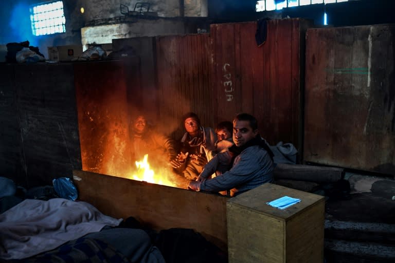 A group of migrants gather around a bonfire in a makeshift shelter inside an abandoned warehouse in Belgrade