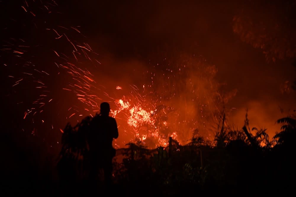 A man stands next to a fire in agricultural land in Kampar, in Sumatra island’s Riau province on September 16, 2019 as the city is blanketed by smoke from fires. — AFP pic