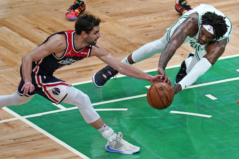 Washington Wizards guard Raul Neto, left, and Boston Celtics center Robert Williams III scramble for the ball during the first half of an NBA basketball Eastern Conference play-in game Tuesday, May 18, 2021, in Boston. (AP Photo/Charles Krupa)