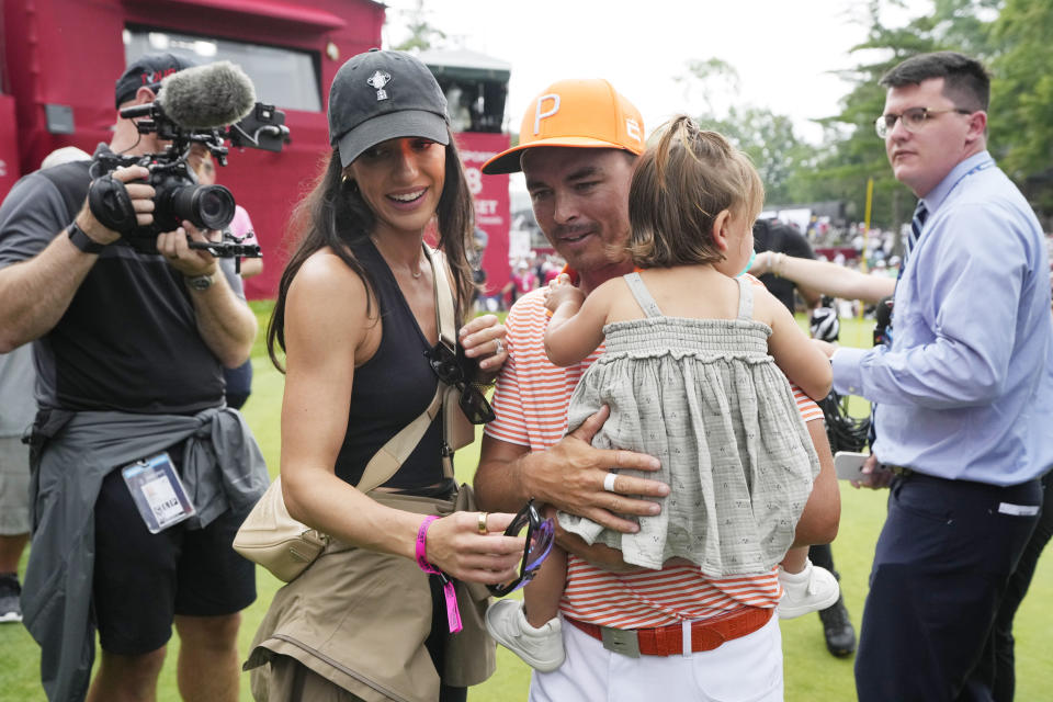 Rickie Fowler walks off the 18th green with his wife Allison Stokke and daughter after the final round of the Rocket Mortgage Classic golf tournament at Detroit Country Club, Sunday, July 2, 2023, in Detroit. (AP Photo/Carlos Osorio)