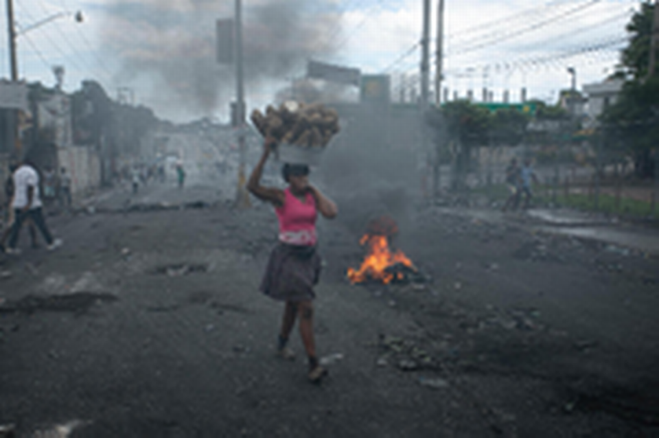 A street vendor walks past a barricade set up by demonstrators to protest against fuel price hikes and to demand that Haitian Prime Minister Ariel Henry step down in Port-au-Prince, Haiti, Monday, Sept. 19, 2022.