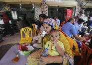 People eat at a restaurant following an ease in restrictions that had been imposed to help control the coronavirus, in Karachi, Pakistan, Monday, Aug. 10, 2020. Pakistan's daily virus infection rate has stayed under 1,000 for more than four weeks prompting the government to further ease restrictions for restaurants, parks, gyms and cinemas. (AP Photo/Fareed Khan)