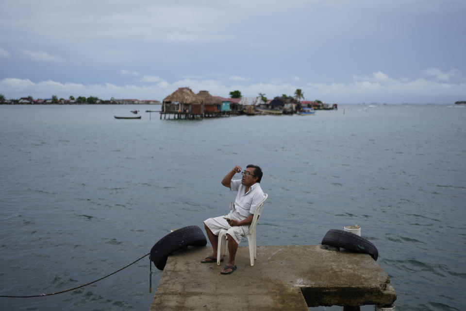 Evelio Lopez tries to get cell phone connection on a dock on Gardi Sugdub Island, part of the San Blas archipelago off Panama's Caribbean coast, Saturday, May 25, 2024. Due to rising sea levels, about 300 Guna Indigenous families will relocate to new homes, built by the government, on the mainland. (AP Photo/Matias Delacroix)