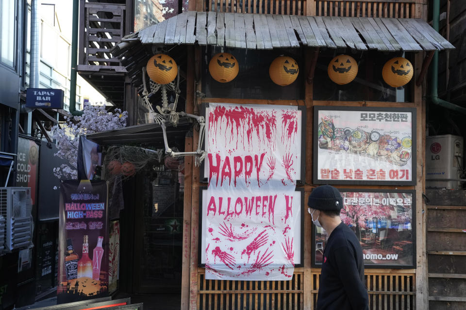 A man walks past Halloween decorations near the scene of a deadly accident following Saturday night's Halloween festivities in Seoul, South Korea, Sunday, Oct. 30, 2022. In this ultra-wired, high-tech country, anguish, terror and grief, as well as many of the details of what happened, are playing out most vividly on social media. Users posted messages desperately seeking friends and loved ones, as witnesses and survivors described what they went through. (AP Photo/Ahn Young-joon)