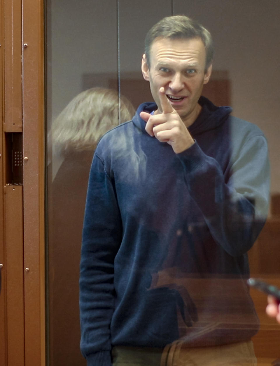 In this photo taken from a footage provided by the Babuskinsky District Court Tuesday, Feb. 16, 2021, Russian opposition leader Alexei Navalny gestures during a hearing on his charges for defamation in the Babuskinsky District Court in Moscow, Russia. Navalny is accused of defaming a World War II veteran who was featured in a video last year advertising constitutional amendments that allowed an extension of President Vladimir Putin's rule. (Babuskinsky District Court Press Service via AP)