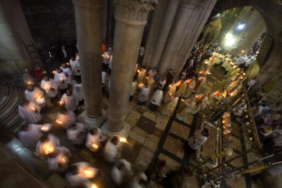 Christian clergymen hold candles during the Easter Sunday procession at the Church of the Holy Sepulchre, traditionally believed by many to be the site of the crucifixion and burial of Jesus Christ, in Jerusalem's Old City, Sunday, April 20, 2014. Millions of Christians around the world celebrated Easter commemorating the day when according to Christian tradition Jesus was resurrected in Jerusalem two millennia ago. (AP Photo/Sebastian Scheiner)