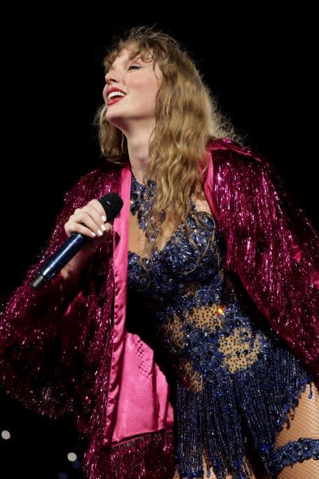 Taylor Swift performs on stage wearing a sequined outfit with a fringed jacket