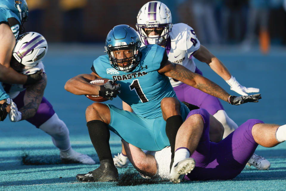 Coastal Carolina running back Braydon Bennett tries to keep his footing as he is tackled by James Madison defensive lineman James Carpenter during the first half of an NCAA college football game in Conway, N.C., Saturday, Nov. 25, 2023. (AP Photo/Nell Redmond)