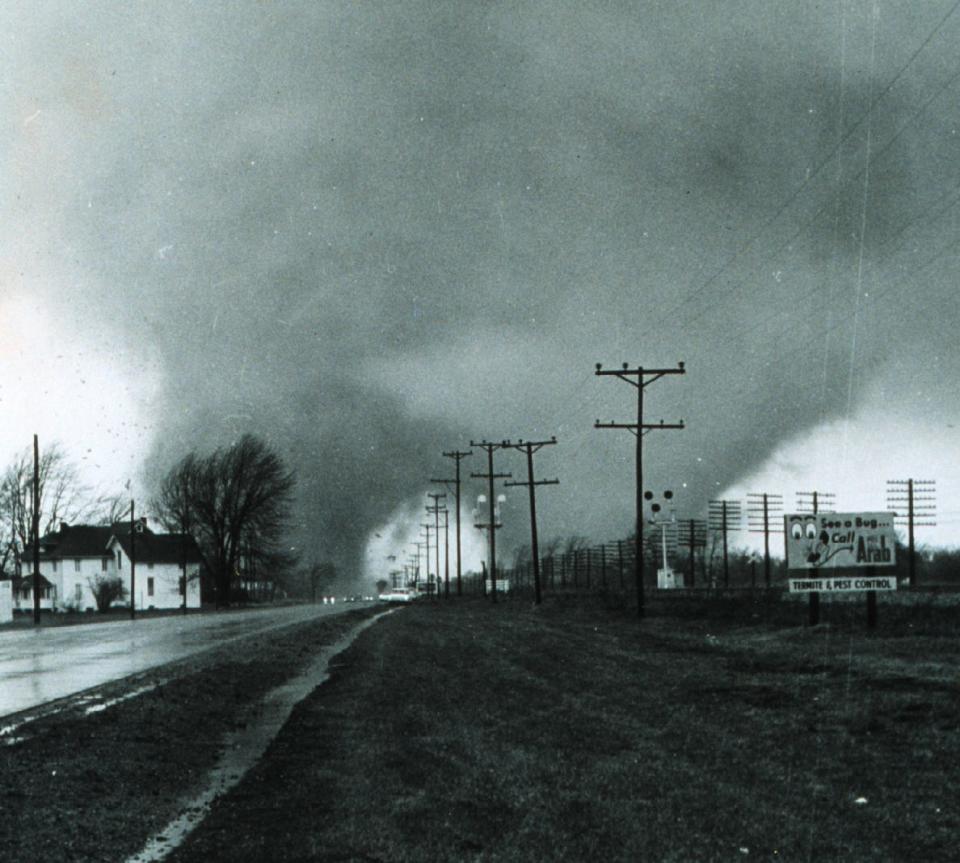 A black-and-white image of two tornadoes side by side near a road