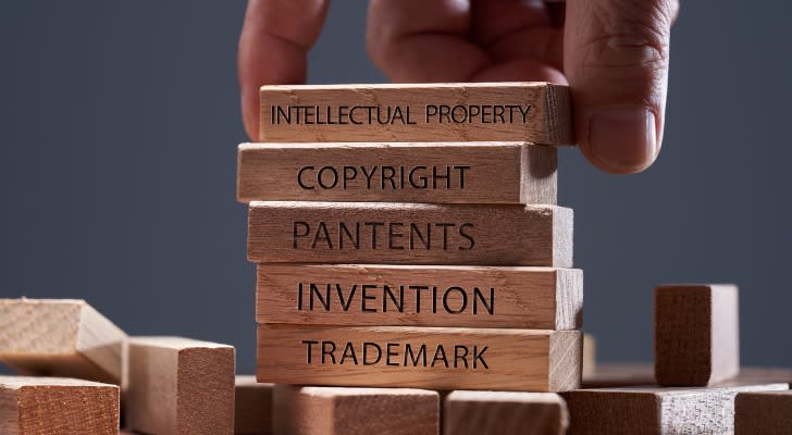 A man adds a block showing the words intellectual property on top of other wooden blocks.