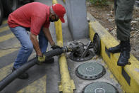 A worker wearing a face mask amid the new coronavirus pandemic works to fills up one of the tanks of a state oil company gas station in Caracas, Venezuela, Sunday, May 31, 2020. After decades of being the cheapest gasoline in the world, Venezuelan President Nicolas Maduro indicates that as of next Monday a new pricing scheme will be imposed on some 200 stations. (AP Photo/Matias Delacroix)